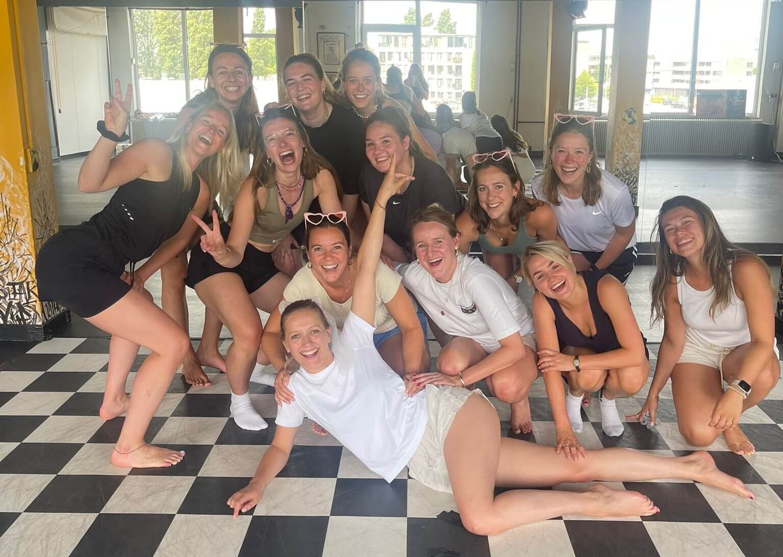 Een gezellige groep vriendinnen die in een workshop leren twerken en de basisbewegingen onder de knie krijgen.