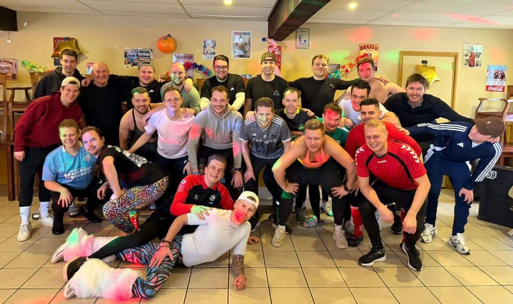 Een grote groep mannelijke collega's geniet van een informeel moment tijdens een actieve workshop bedrijf voor een uniek bedrijfsuitje.