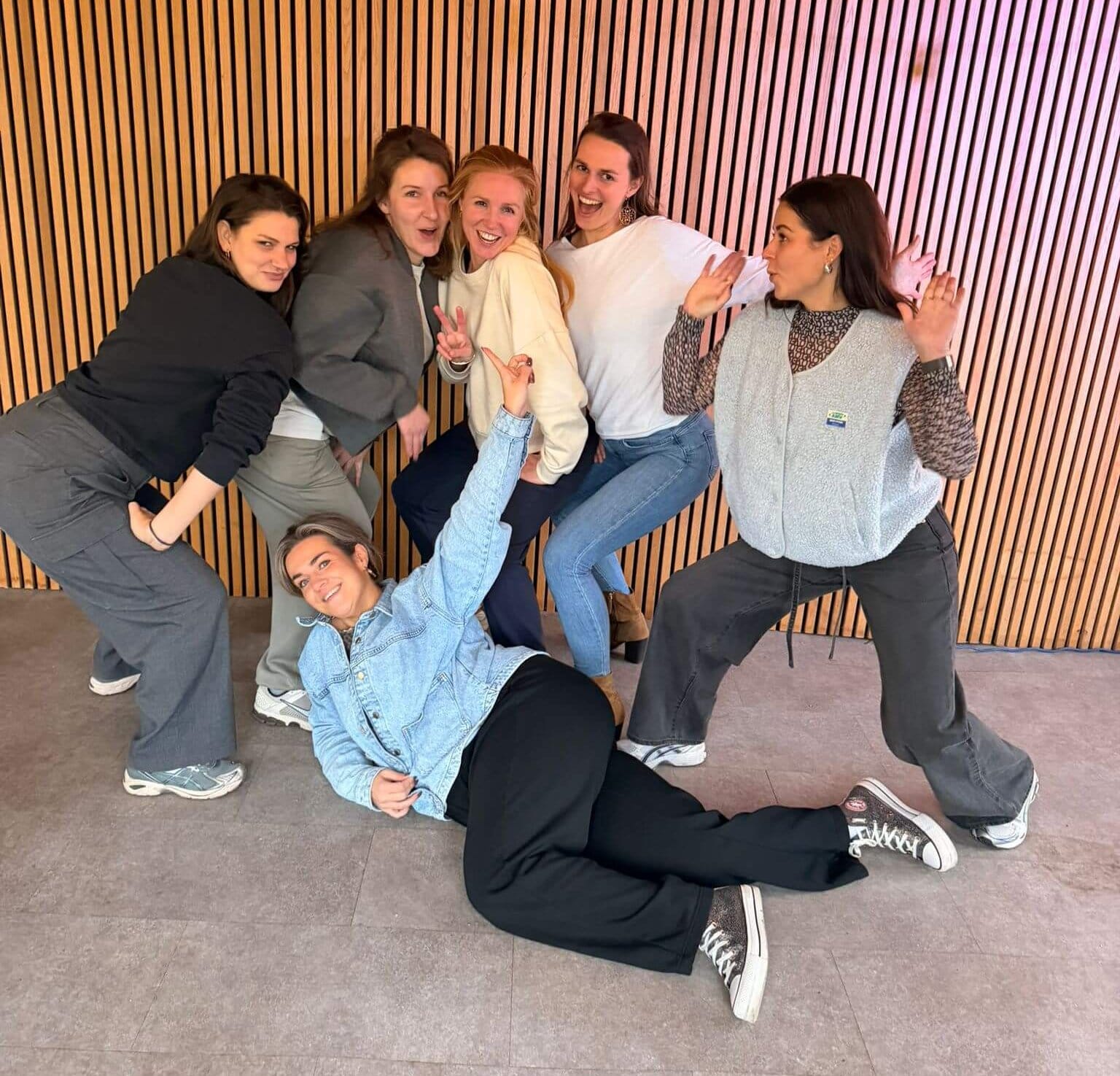 Een vrolijke groep collega's poseert samen na een energieke workshop voor bedrijven die focust op teambuilding en plezier.